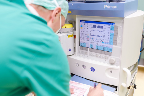 Arzt überträgt medizinische Daten von einem Monitor in ein Formular