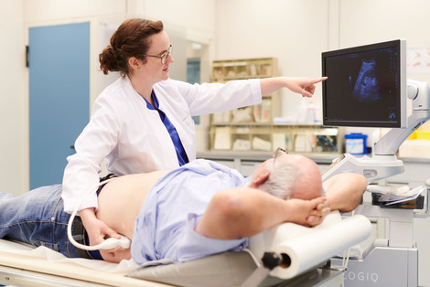 Ärztin führt eine Ultraschalluntersuchung aus und erklärt dabei dem Patienten, was auf dem Monitor zu sehen ist